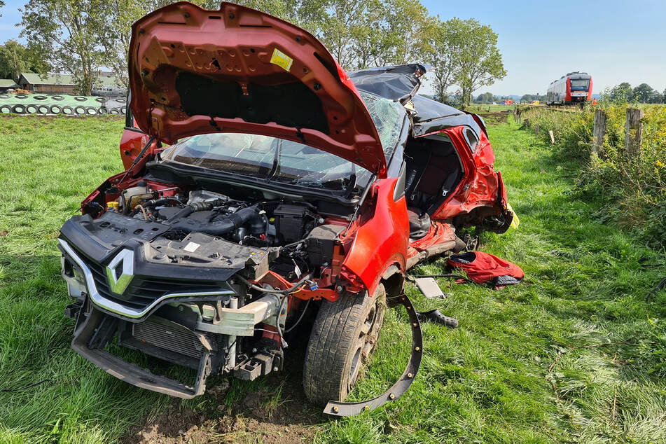 Das völlig zerstörte Auto steht nach dem Crash am Bahnübergang auf einer Wiese.
