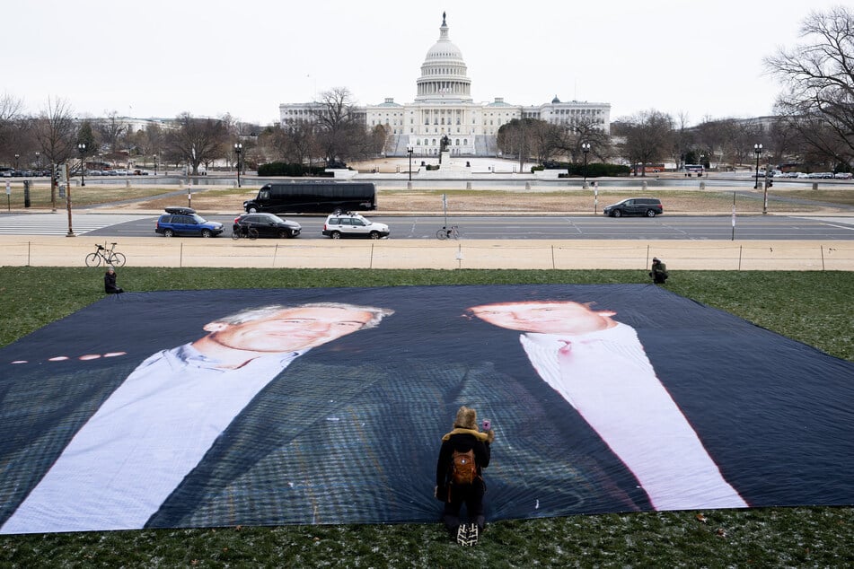 Activists with Glasgow Actions Team and Everybody Hates Elon unveil a banner featuring a photo of Donald Trump and Jeffrey Epstein in Washington DC on December 15, 2025.