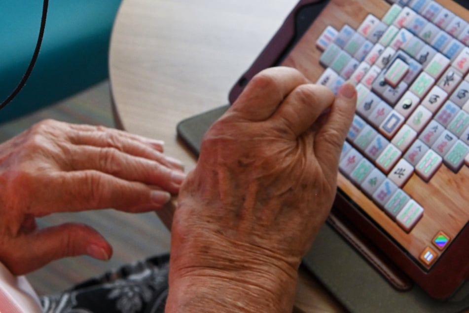 Eine Frau spielt im Seniorenheim mit ihrem Tablet Mahyong.