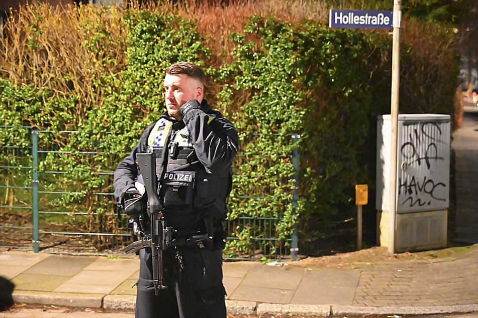 Ein mit Maschinenpistole bewaffneter Polizist sichert die Zufahrt zur Hollestraße.