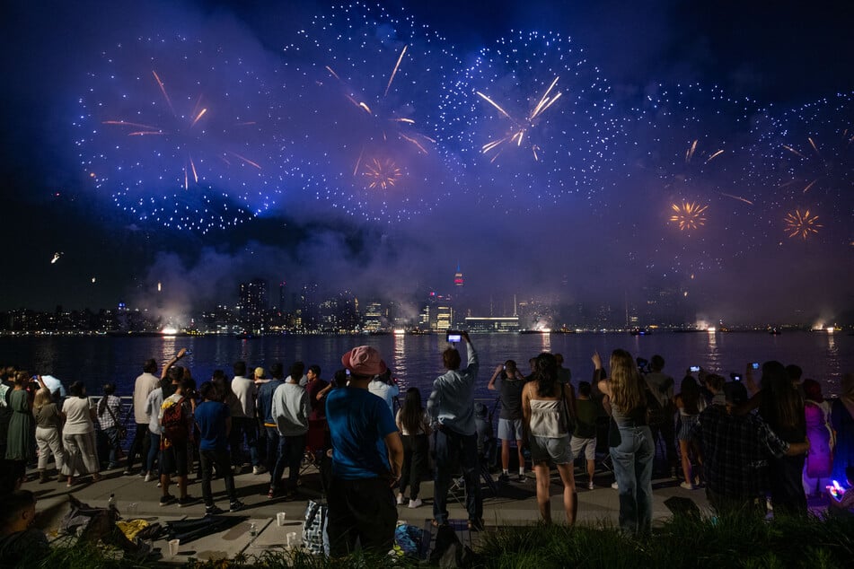 People watch as fireworks explode over the Manhattan skyline during Macy's Independence Day fireworks display in New York City on July 4, 2023.
