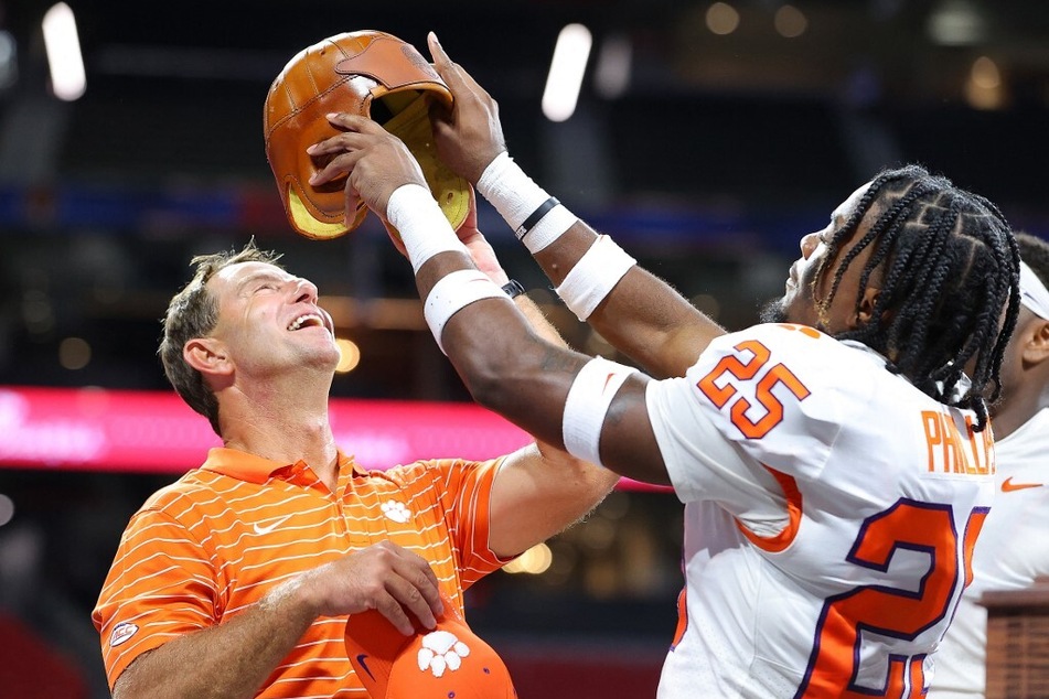 Jalyn Phillips tries to put the Old Leather Helmet on head coach Dabo Swinney of the Clemson Tigers after their season opener 41-10 win over the Georgia Tech.