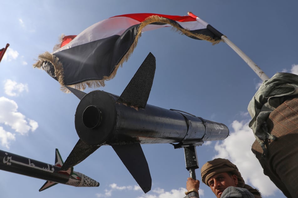 Ein Huthi-Anhänger trägt die Nachbildung einer Rakete in seinen Händen.