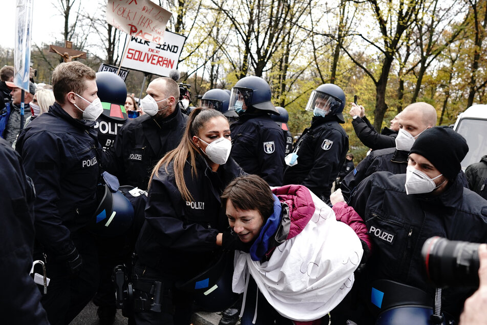 Einsatzkräfte der Polizei halten eine Teilnehmerin einer Demonstration gegen die Corona-Einschränkungen der Bundesregierung vor dem Brandenburger Tor fest.