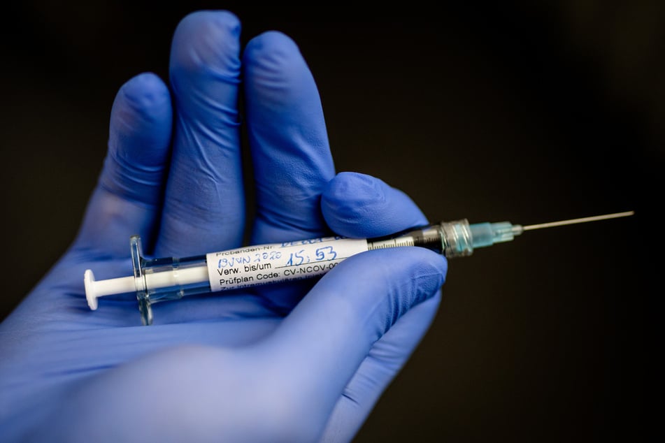 Ein Mann hält im Institut für Tropenmedizin an der Uniklinik Tübingen eine Spritze in der Hand, mit der einer jungen Frau, die erste Probandin, ein möglicher Wirkstoff gegen das Coronavirus gespritzt wurde.