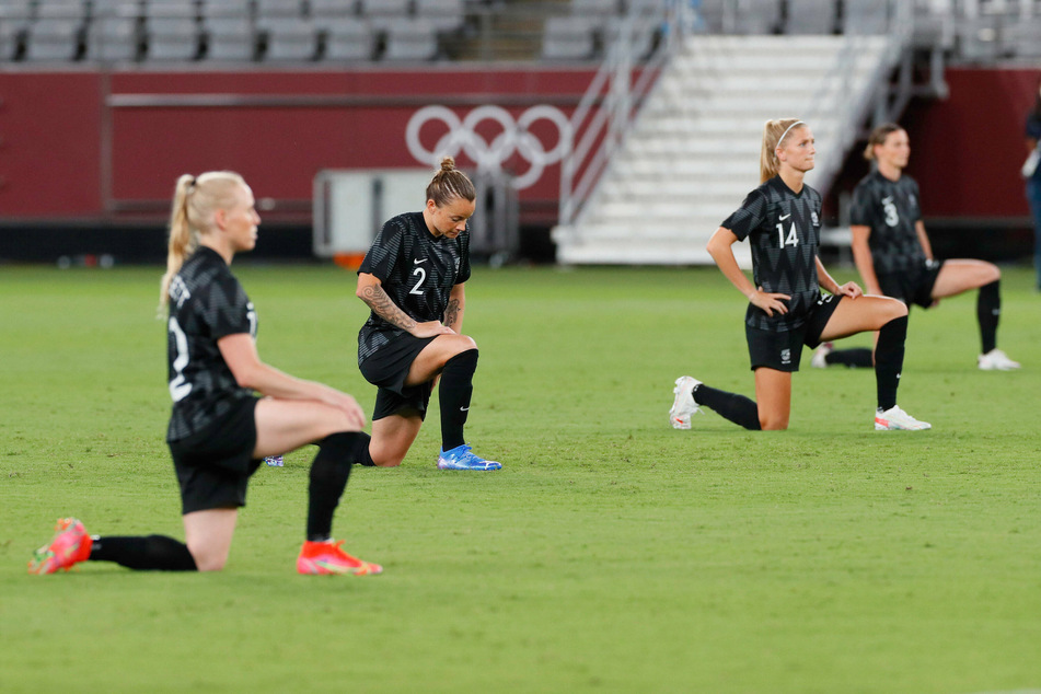 Members of New Zealand's women's soccer team kneel ahead of a match during the 2020 Tokyo games.