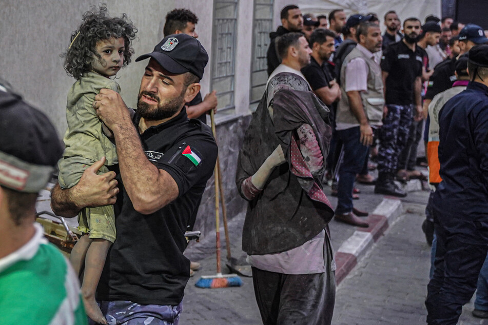 Ein palästinensischer Polizist hält ein Kind, nachdem es aus dem Bombardierungsgebiet gebracht wurde.