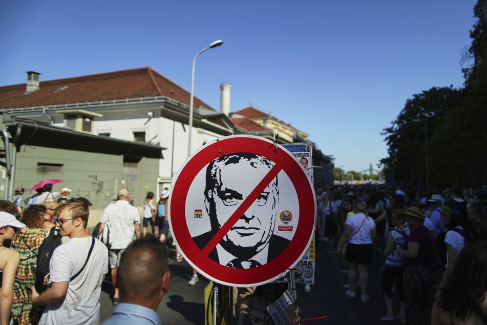 Des participants de la marche des fiertés à proximité d'un panneau d'"interdiction" sur lequel on aperçoit le premier ministre hongrois Viktor Orban (62).