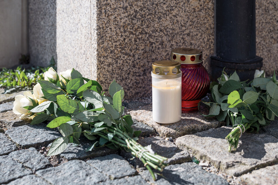 An der Straßenecke zur Zufahrtsstraße zum Kinder- und Jugendhilfezentrum, in dem eine Zehnjährige tot aufgefunden wurde, liegen Blumen und Grablichter auf dem Gehweg.