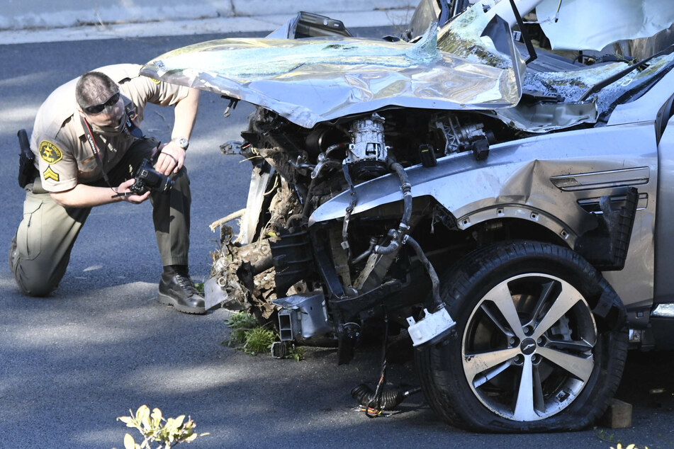 A police officer documents the damage to Woods' car.