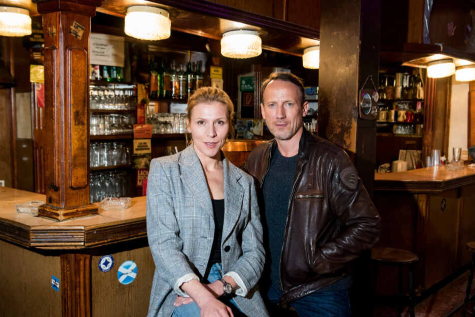 Das Ermittler-Duo steht in einer Kneipe vor einer Bar.