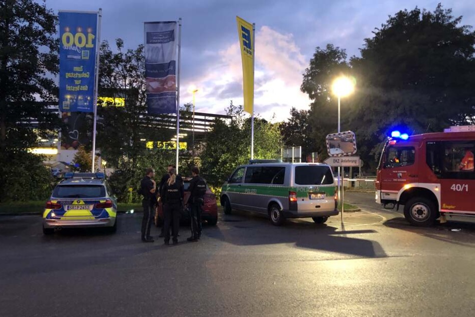 Fahrzeuge von Polizei und Feuerwehr stehen vor einem Supermarkt in dem Schüsse gefallen sind.