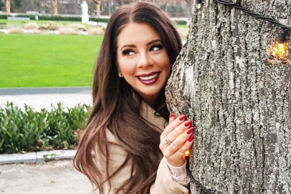 Jenny Frankhauser versteckt sich hinter einem Baum.
