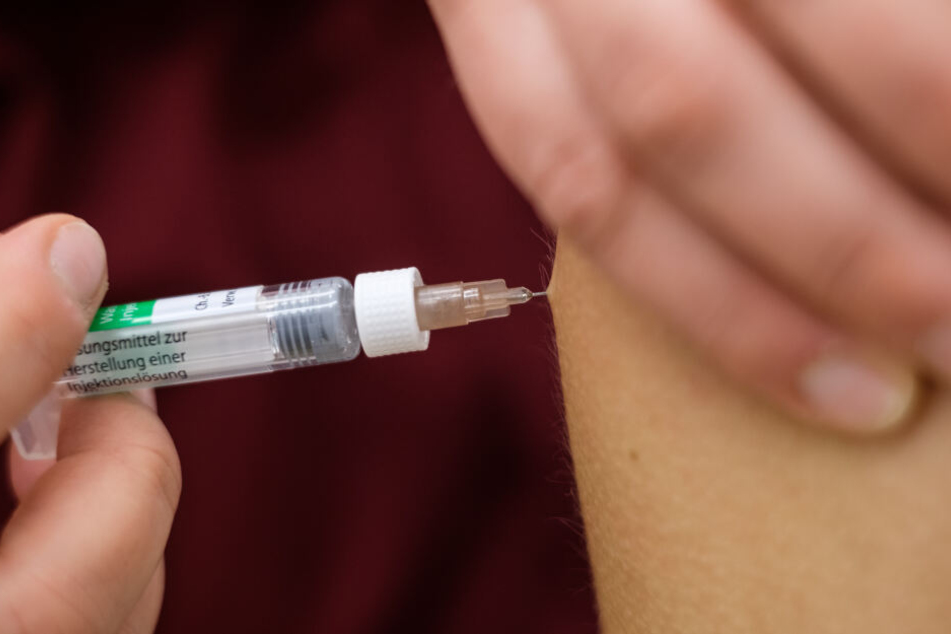Eine Arzthelferin impft in einer Arztpraxis eine Patientin mit einer Spritze.