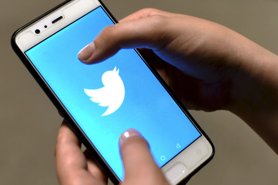 Auf dem Handy-Display wird das Twitter-Logo angezeigt.