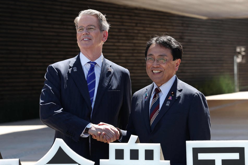 US Treasury Secretary Scott Bessent (L) shakes hands with Japan's economic revitalisation minister and chief negotiator in trade tariff talks, Ryosei Akazawa (R), in front of the US pavilion at the Osaka Expo as they attend US national day celebrations, in the city of Osaka on July 19, 2025.
