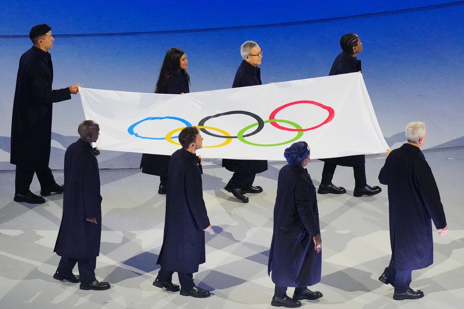 Offizielle tragen während der Eröffnungsfeier die Olympische Flagge.