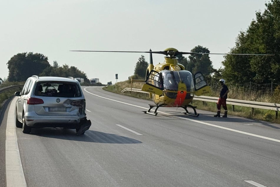 Ein Rettungshelikopter vom ADAC kommt auf der komplett in Richtung Dresden gesperrten A4 zum Einsatz. Daneben steht ein beschädigter VW.