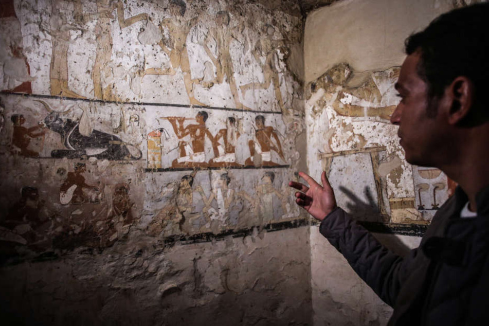 Ein Mitarbeiter der Ausgrabungen deutet auf die Wandmalereien in einem neu entdeckten Grab in der Nähe der Cheops-Pyramiden in Gizeh.