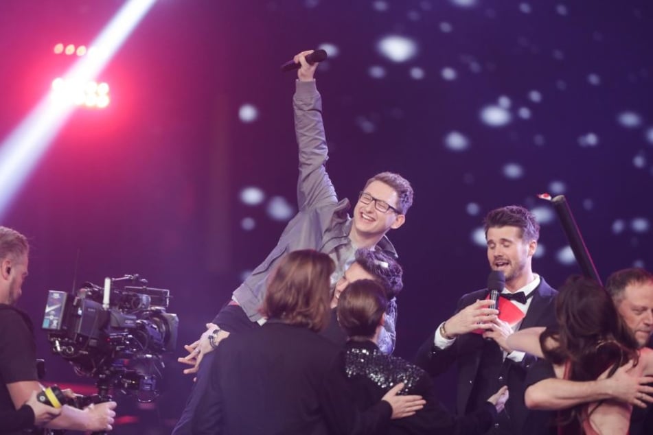 Der Kandidat Samuel Rösch (M) jubelt über seinen Sieg bei der Castingshow "Voice of Germany" auf der Bühne.