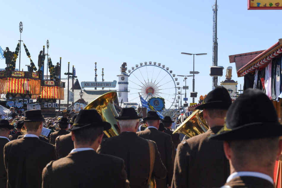 Auftakt zum Oktoberfest 2019. Eine Blaskapelle geht beim Einzug der Festwirte über die Theresienwiese auf das Riesenrad zu.