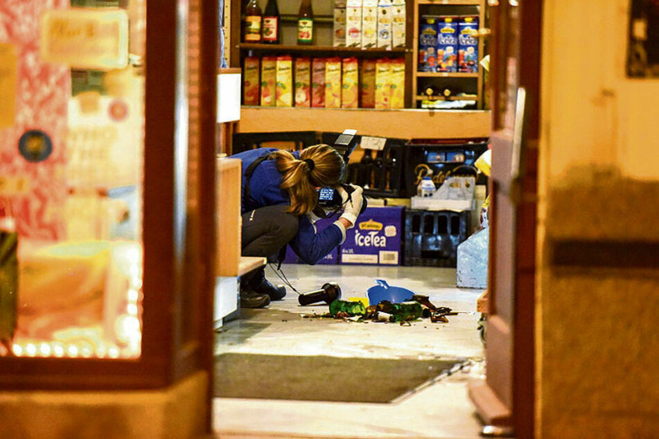 Eine Kriminaltechnikerin fotografiert im Laden die Spuren des Überfalls.