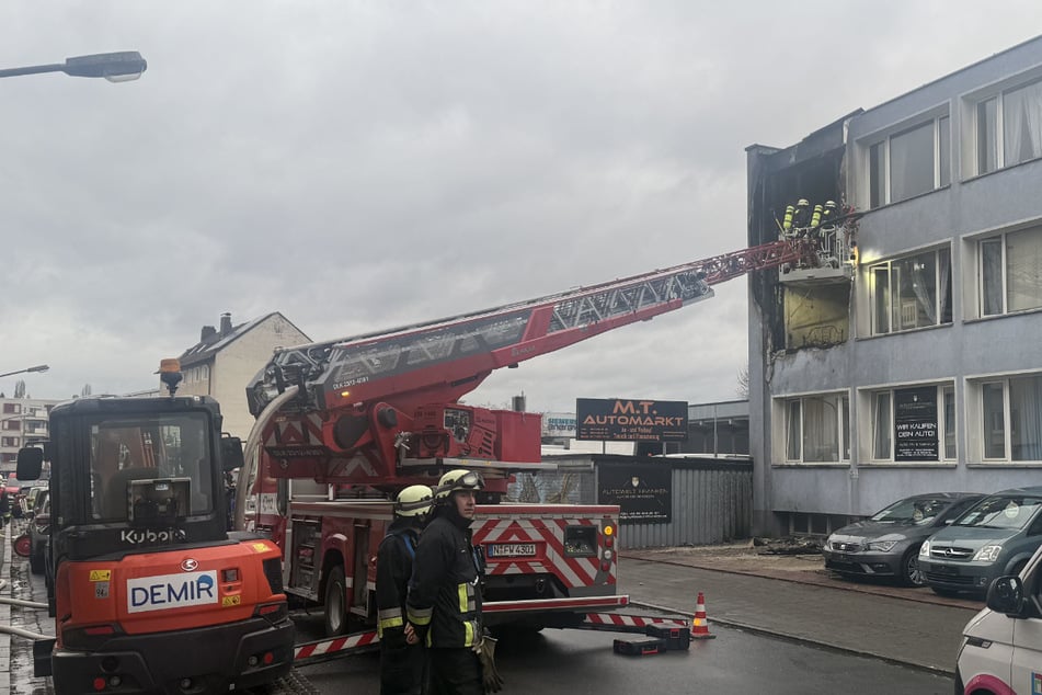 Feuerwehrleute begutachten die zwei Brandwohnungen in der Erlenstraße über eine Drehleiter.