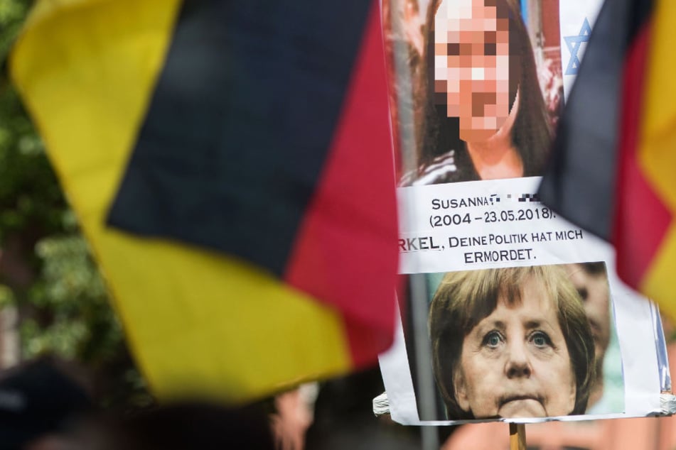 Ein Teilnehmer der Kundgebung der Initiative "Beweg was!" hält ein Plakat mit einem Bild der ermordeten Susanna und von Bundeskanzlerin Angela Merkel.