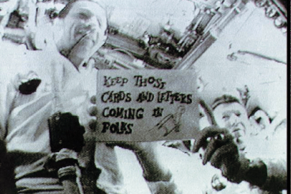 Walter Schirra and Donn Fulton Eisele holding up a sign during the Apollo 7 space mission.