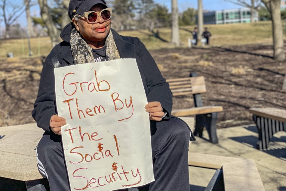 A protester holds a sign reading "Grab Them By the Social Security" in a rally outside the Social Security Administration headquarters.