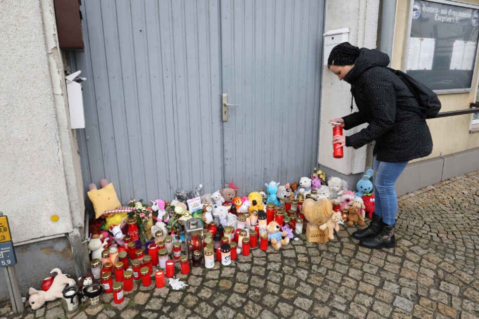 Eine Frau stellt vor dem Haus in Torgelow eine Kerze auf, wo am 12.01.2019 ein sechsjähriges Mädchen ums Leben kam.