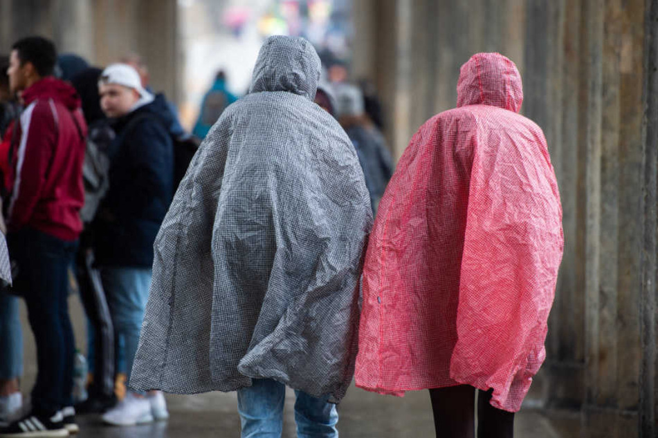 Touristen schützen sich in Regencapes vor den Niederschlägen.