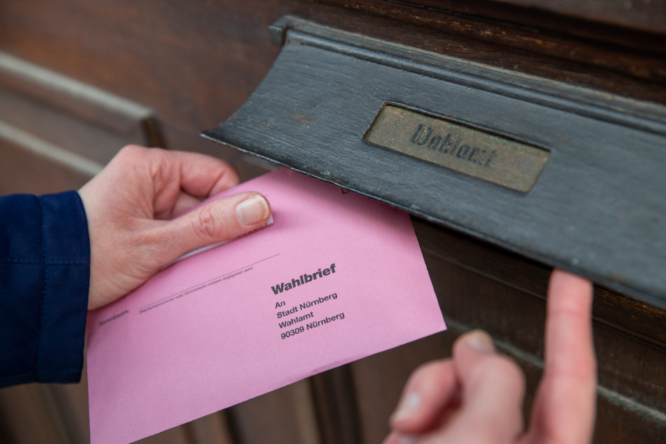 Eine Frau wirft ihre Briefwahlunterlagen für die Oberbürgermeister-Stichwahl am 29. März in Nürnberg in den Briefkasten des Wahlamtes.