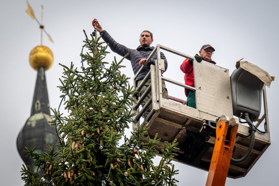 Sebastian Baier (25, l.) vom Ingenieurbüro Wuttke hält für die Vermessung ein Mini-Prisma an die Spitze des Chemnitzer Weihnachtsbaums.