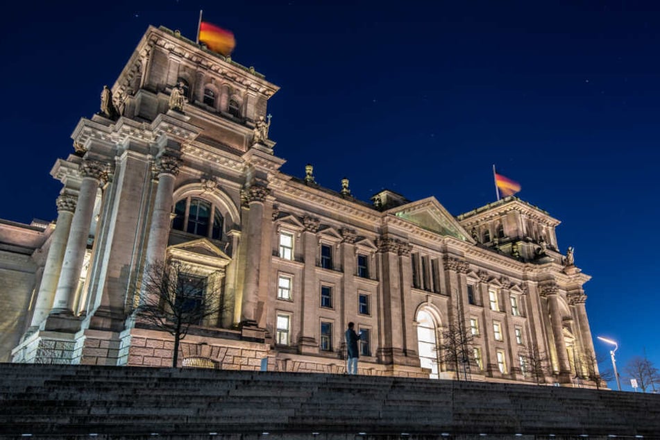 Ein Mann steht am Abend vor dem Reichstag. (Symbolbild)