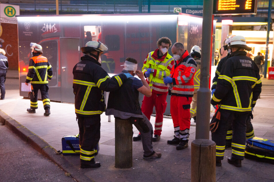 Mitarbeiter der Rettungsdienstes versorgen einen am Kopf verletzten Mann am Bahnhof Elbgaustraße.