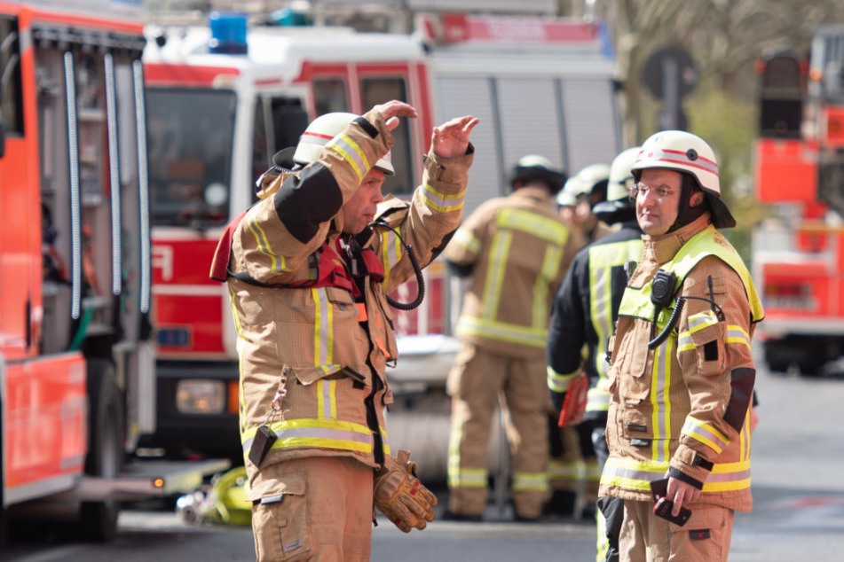 Feuerwehrleute stehen auf der Straße vor dem Haus und bereiten Nachlöscharbeiten vor (Symbolbild).