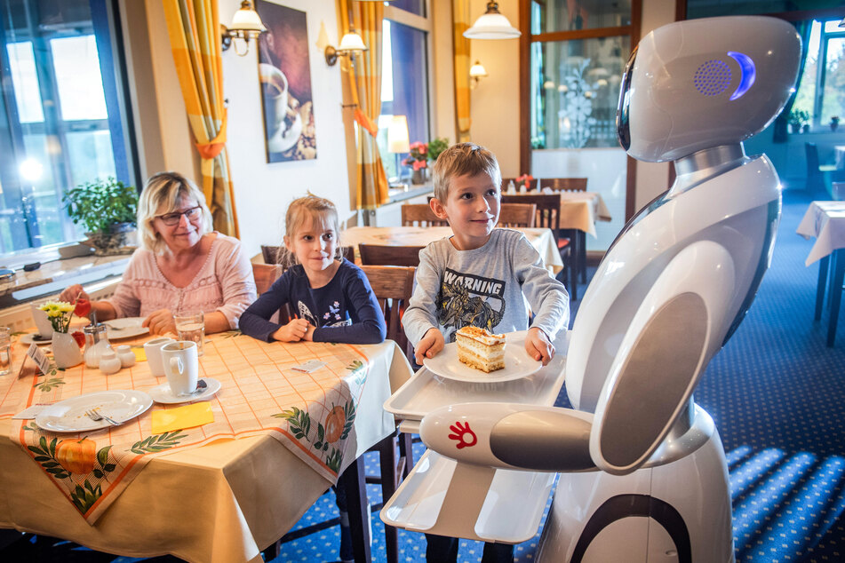 "Amy" serviert Hannelore Kossack (64) und ihren Enkeln Mia und Max (beide 6) ein Stück Kuchen.