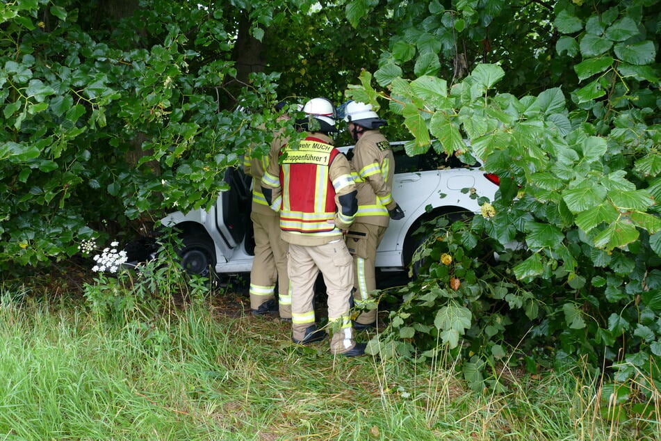 Einsatzkräfte der Feuerwehr beraten sich, wie sie den Unfallwagen der Gummersbacherin aus dem Gebüsch bekommen.