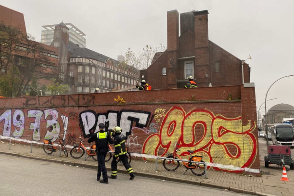 Feuerwehrleute untersuchen die Baustelle, aus der Rauch aufsteigt.