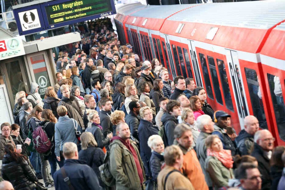 Dicht gedrängt stehen Fahrgäste in Hamburg neben einer einfahrenden S-Bahn.