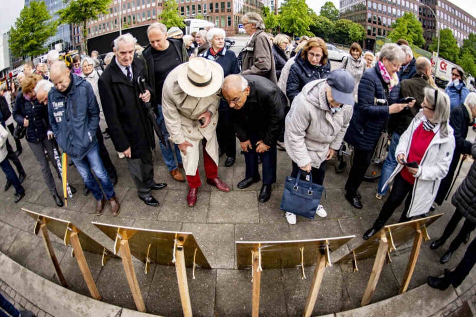 Menschen betrachten die vor der Verlegung von vier aufgestellten neuen Michel-Tafel.