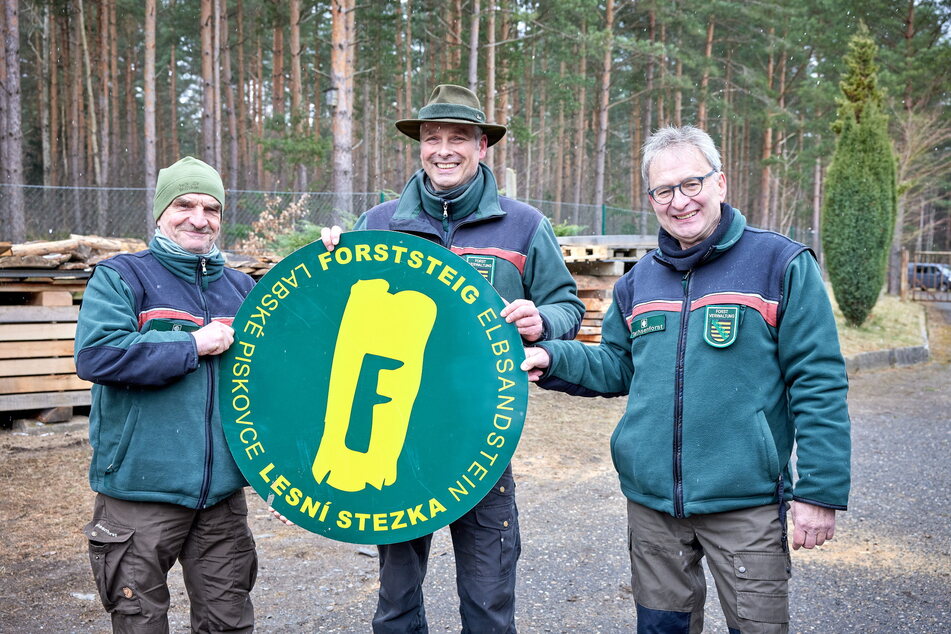 Forstleute um Forstbezirksleiter Uwe Borrmeister (51, M.) mit dem Logo des Wanderweges.