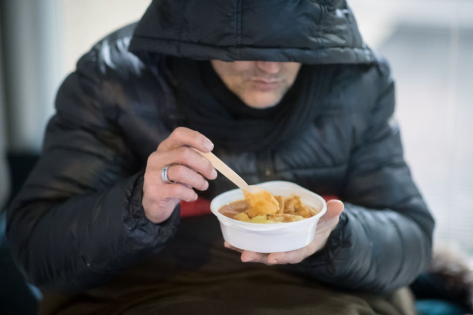 Ein Obdachloser ist in einer Wärmestube eine Mahlzeit.