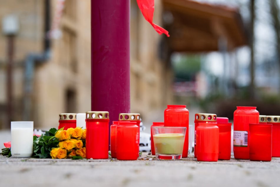 Kerzen und Blumen liegen vor dem Tatort.