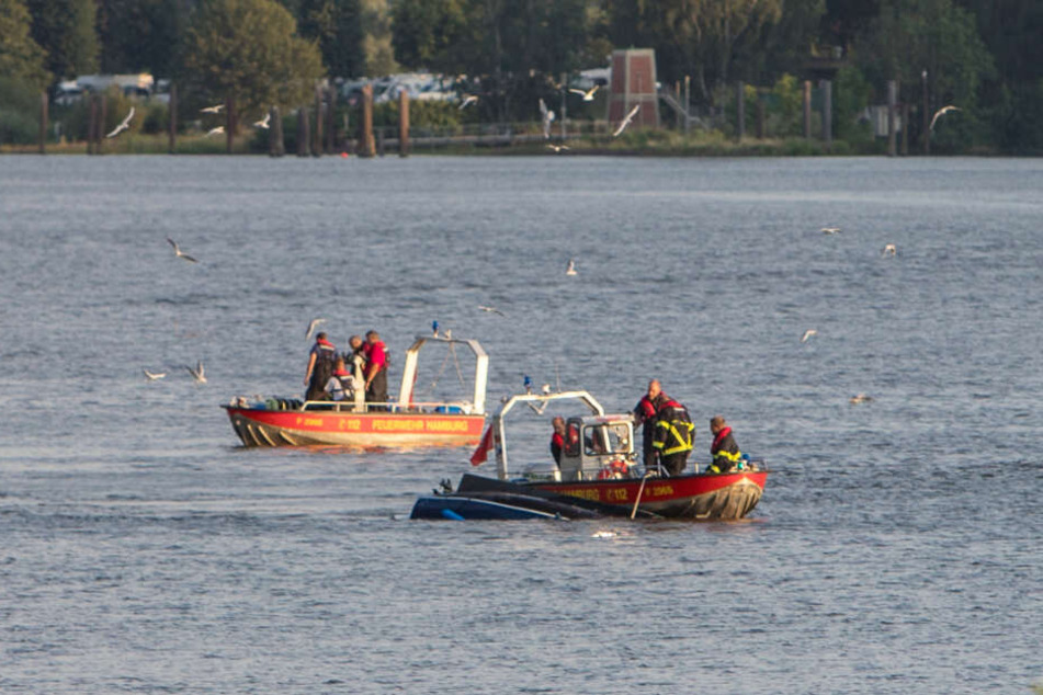 Feuerwehrboote sichern das kieloben treibende Boot.