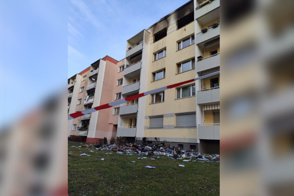 Brandgut und verbrannte Gegenstände liegen vor dem Haus.