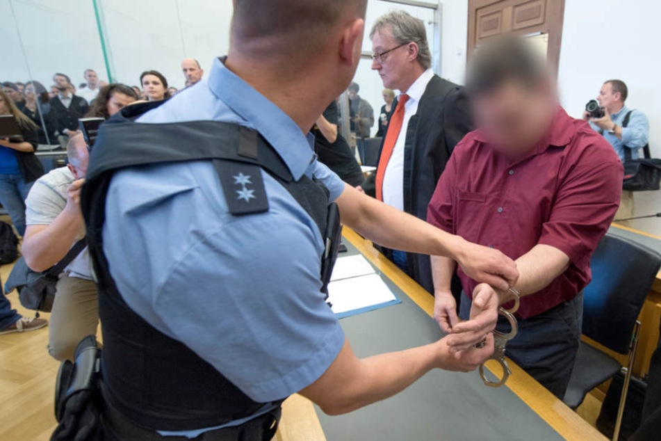 Der 42-jährige Angeklagte wird zur Anklagebank im Verhandlungssaal des Landgerichts in Gießen geführt.