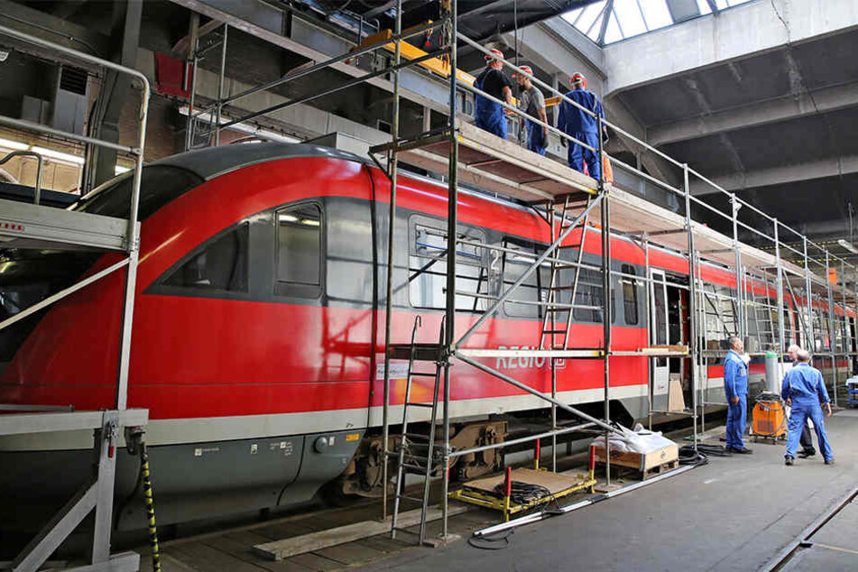 Mitarbeiter der Erzgebirgsbahn montieren Zusatzaggregate auf das Dach eines Triebwagens der Baureihe 642.