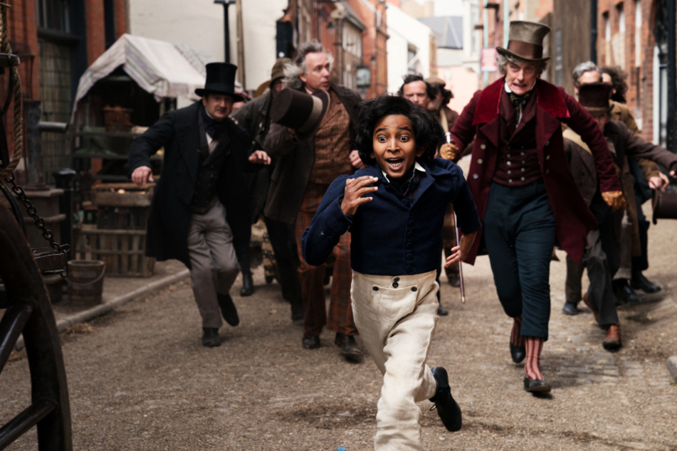 Auf der Flucht: David Copperfield (vorne; Jairaj Varsani) flieht gemeinsam mit Mr. Micawber (vorne-rechts; Peter Capaldi) vor den vielen Schuldeneintreibern.